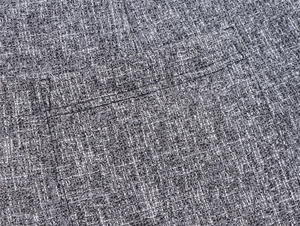 Close-up of grey tweed fabric texture and precise stitching on the suit pocket detail