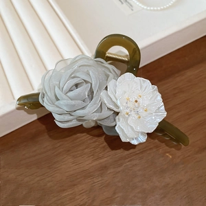 Dettaglio ravvicinato di rosa in chiffon blu e fiore di acrilico bianco su elegante pinza