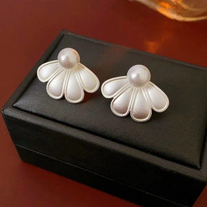 Detailed view of silver flower petal earrings with artificial pearls on a jewelry box