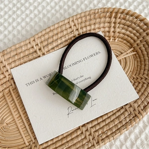 Close-up of dark green acetate rectangle hair tie with gold France Handmade lettering