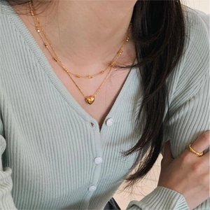 Detail of layered gold heart necklace and matching gold ring on a female model