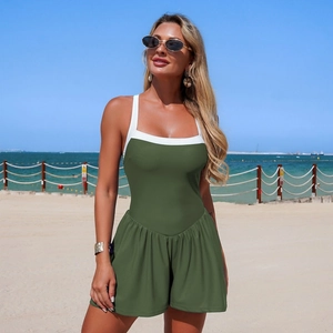 Detail of dark green one-piece swimsuit with white contrast straps on sunny beach