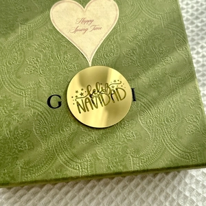 Detail of green gift box with vintage floral embossing and Feliz Navidad gold sticker