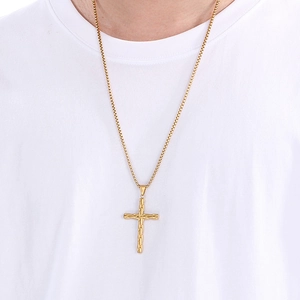 Detailed view of a gold cross pendant with textured finish on a classic box chain