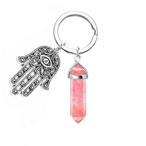 Detail of pink crystal hexagonal pillar and silver Hamsa hand charm on a key ring