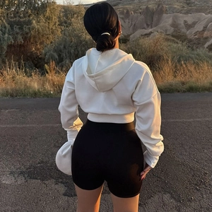 Back view of white cropped hoodie and black high waist shorts on a sunset road