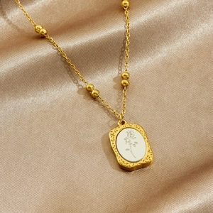 Vintage gold plated stainless steel rose oval pendant necklace on silk background