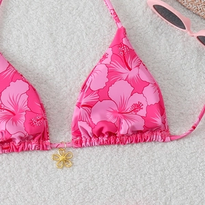 Detailed close-up of pink floral bikini top with ruffled triangle cups and gold charm