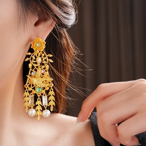 Primer plano de pendientes dorados con perlas y motivos florales en una modelo