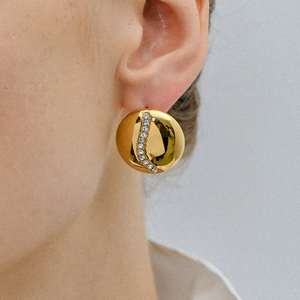 Polished 18k gold plated dome earrings with center zircon stones worn by a model