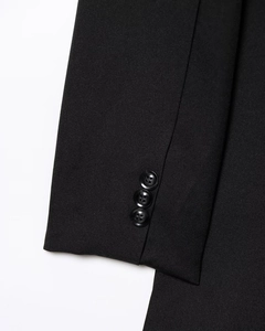 Detail view of high-quality black blazer sleeve featuring three polished buttons and twill fabric