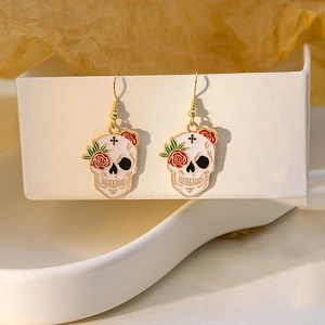 Gothic skull and red rose drop earrings with gold hooks on a warm background display