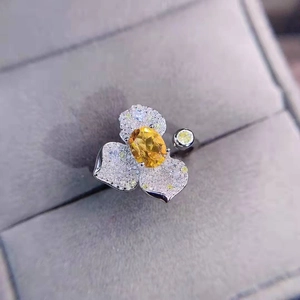 Macro shot of silver ring featuring yellow oval gemstone and micro-pave flower petals