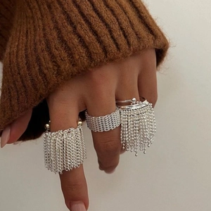 Silver multi-piece ring set with tassels and chains shown on a model's hand