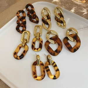 Flat lay of leopard print resin and gold chain earrings on a white ceramic plate