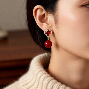 Vintage floral drop earrings with red stones and pearls worn with a beige sweater