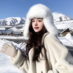 Winter plush trapper hat in white faux fur worn by a woman in a snowy mountain landscape