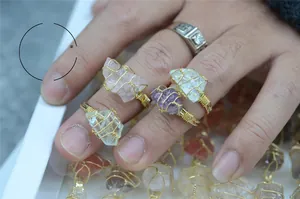 Detail of handmade gold wire wrapped raw amethyst and quartz natural stone rings
