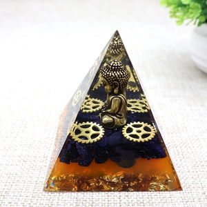 Detailed view of resin pyramid with gold Buddha statue, blue crystals and metal gears