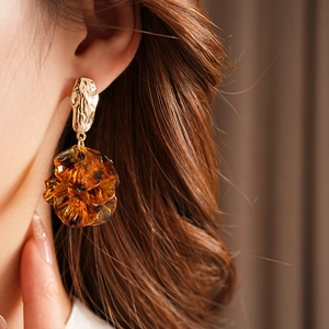 Detail view of model wearing vintage golden petal earrings with amber translucent resin
