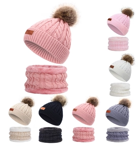 Close-up of winter knit hat and scarf sets with faux fur pom-poms in various colors