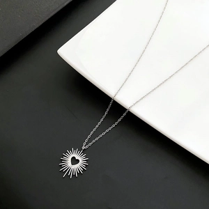 Macro detail of silver heart pendant with sunburst texture on a sleek O-chain necklace