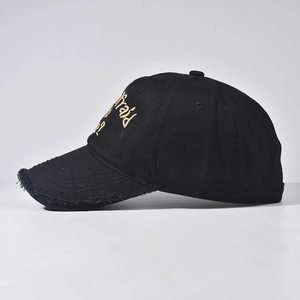 Close-up of golden script embroidery and distressed brim on a vintage black baseball cap