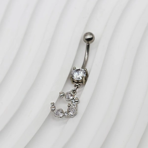 Détail d'un piercing de nombril argenté avec pendentif lune en zircon et cœurs