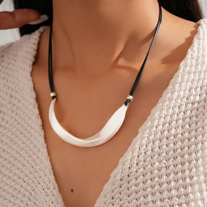 Close-up of a minimalist silver crescent moon pendant necklace on a beige knit sweater