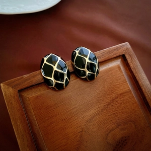 Detailed view of vintage black enamel geometric stud earrings with gold grid pattern