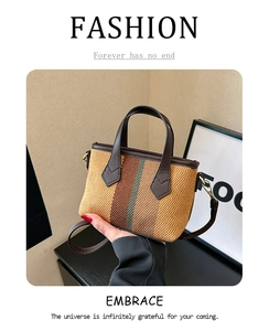 Detail of mini straw woven tote with colorful stripes and dark brown leather trim