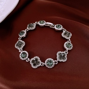 Détail d'un bracelet vintage argenté avec pierres vertes sur du satin rouge