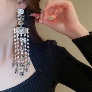 Macro detail of long silver fringe earrings with sparkling geometric crystals on a model