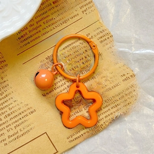 Detail shot of an orange star keychain with small bell on vintage newspaper background