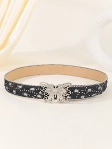 Close-up of black canvas belt with silver sequins and butterfly buckle over jeans