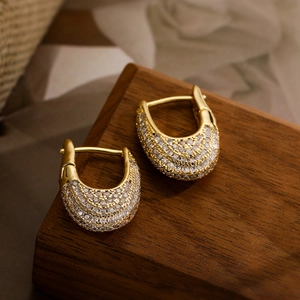 Exquisite 18K vergoldete U-förmige Ohrringe mit Zirkonia-Pflaster auf dunklem Holzgrund