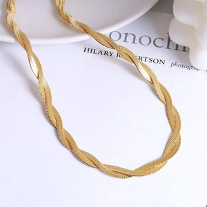 Elegantly twisted gold snake chain necklace displayed on a minimalist white aesthetic background