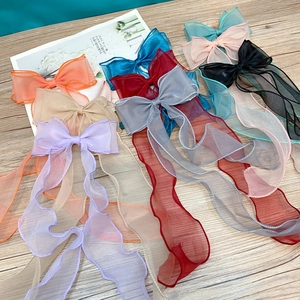 Colorful organza bow hair clips with long streamers arranged on a light wood background