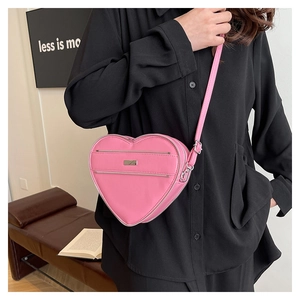 Detail of pink heart-shaped crossbody bag with silver zippers and fine shoulder strap