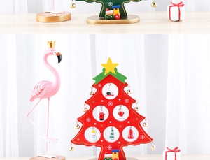 Close-up of a red wooden mini Christmas tree with small hanging snowman and Santa ornaments