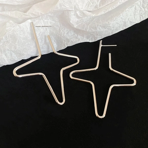 Macro detail of silver geometric star stud earrings on elegant textured background