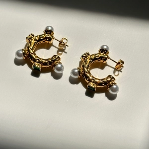 Vintage gold C-shape earrings with white pearls and green square gemstones on white background