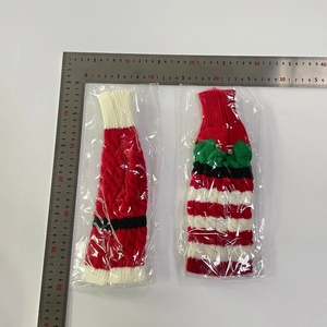 Close-up of knitted Christmas wine bottle covers with belt motifs and gold bells
