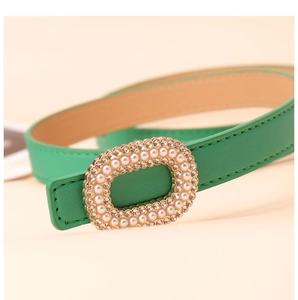 Close-up of green leather belt with elegant oval pearl and rhinestone buckle detail