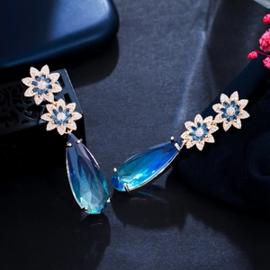 Detail of luxury teardrop sapphire blue pendant earrings with elegant flower rhinestones