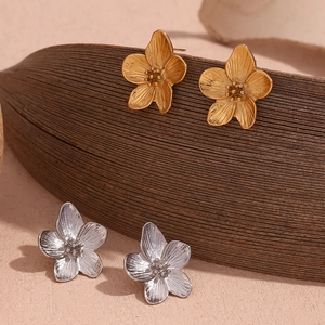 Macro shot of 18K gold and silver plated flower stud earrings with brushed metal texture