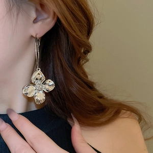 Primo piano di una modella che indossa grandi orecchini a fiore in metallo argentato