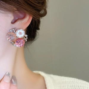 Close-up of model wearing floral stud earrings with pink and white resin flower petals