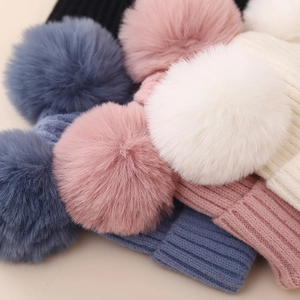 Detailed close-up of colorful winter knit beanies with fluffy pom-poms for girls