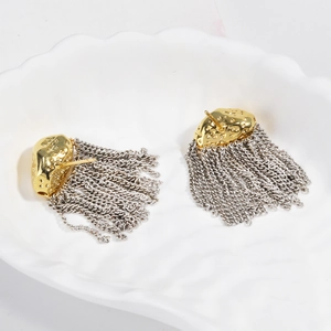 Gros plan de boucles d'oreilles bicolores martelées avec glands argentés sur disque